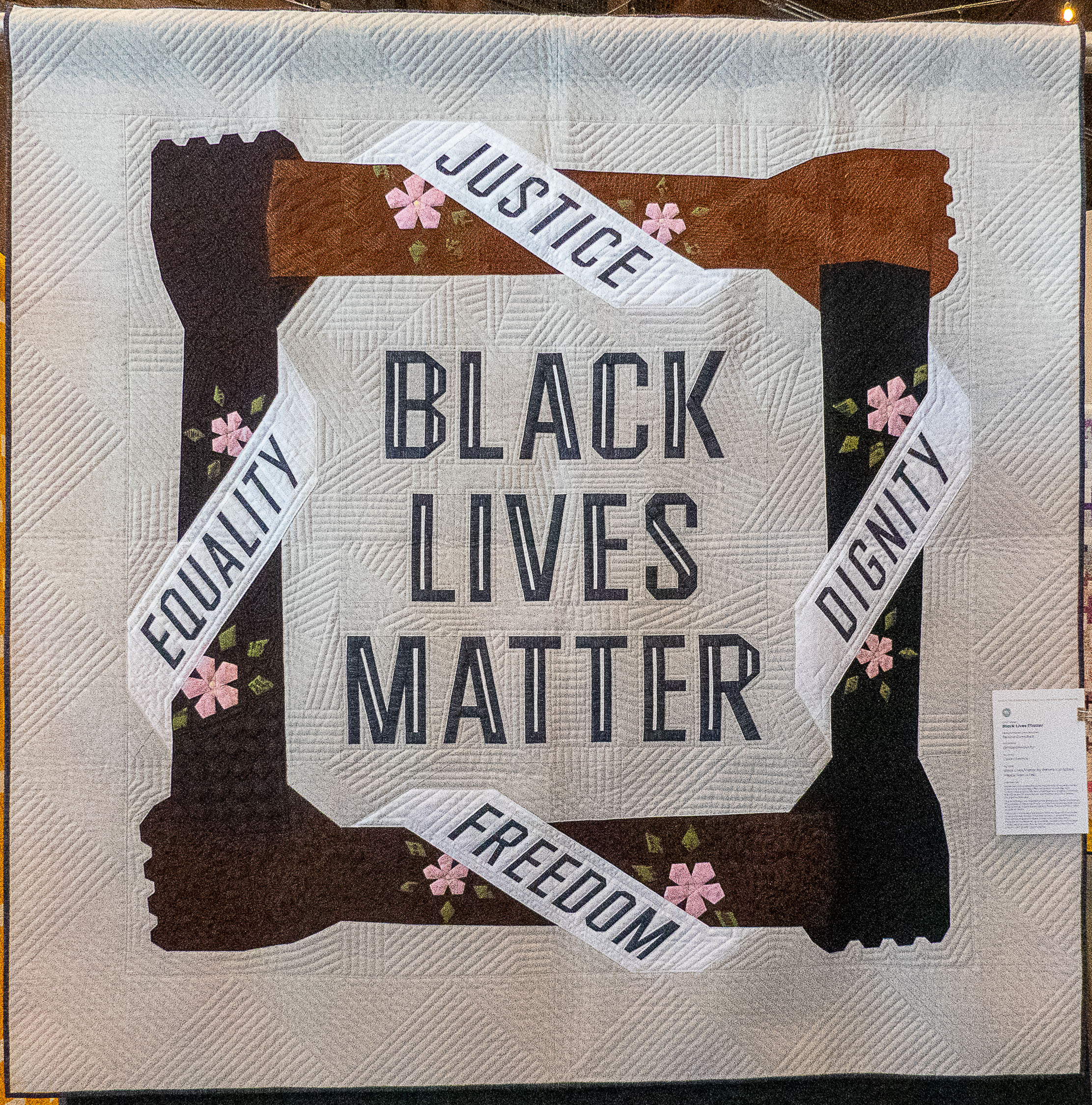 modern quilt with interlocking arms and words: Justice, dignity, freedom, equality