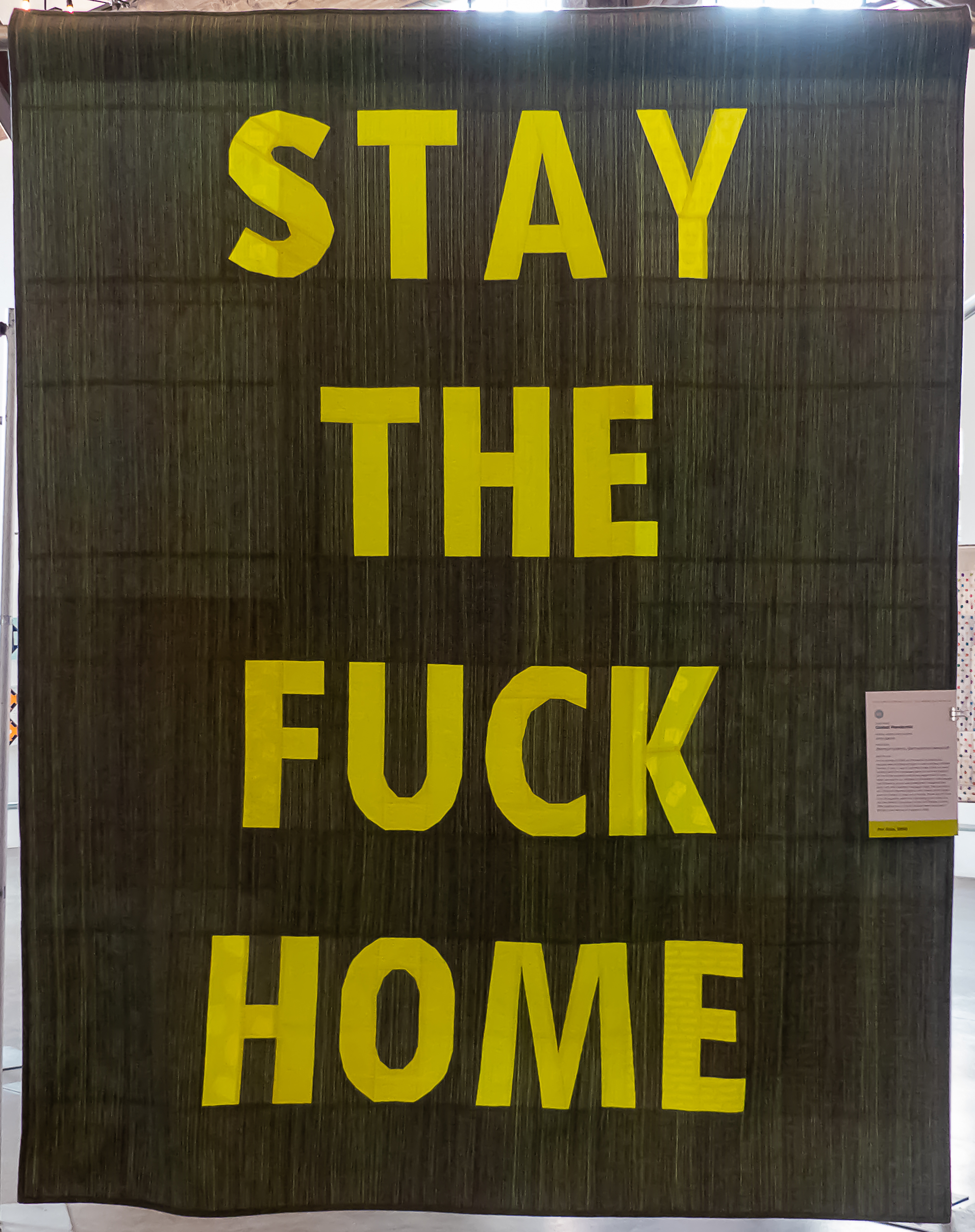 modern quilt with the words "stay the fuck home"