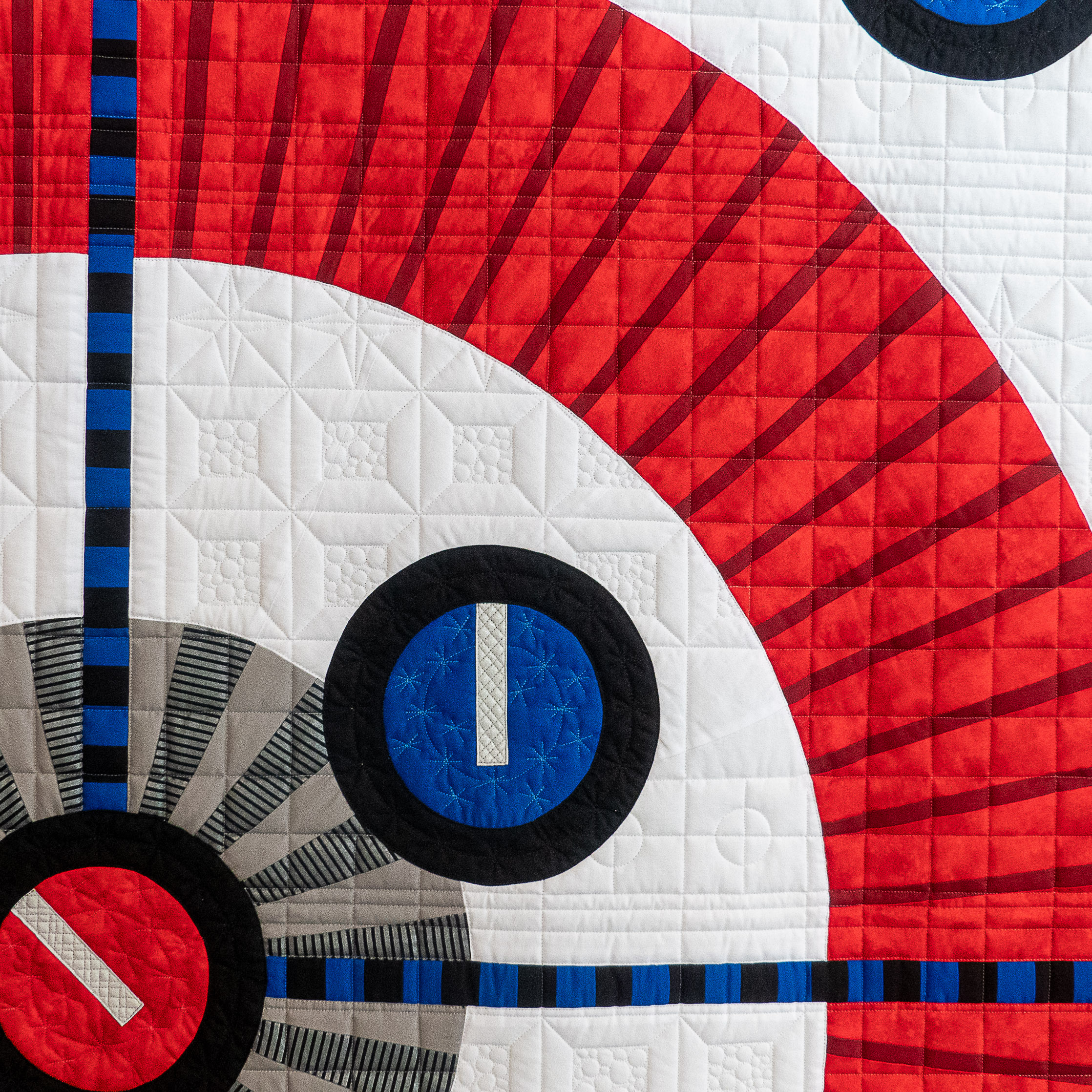 detail of a modern geometric quilt in black, red, blue and black